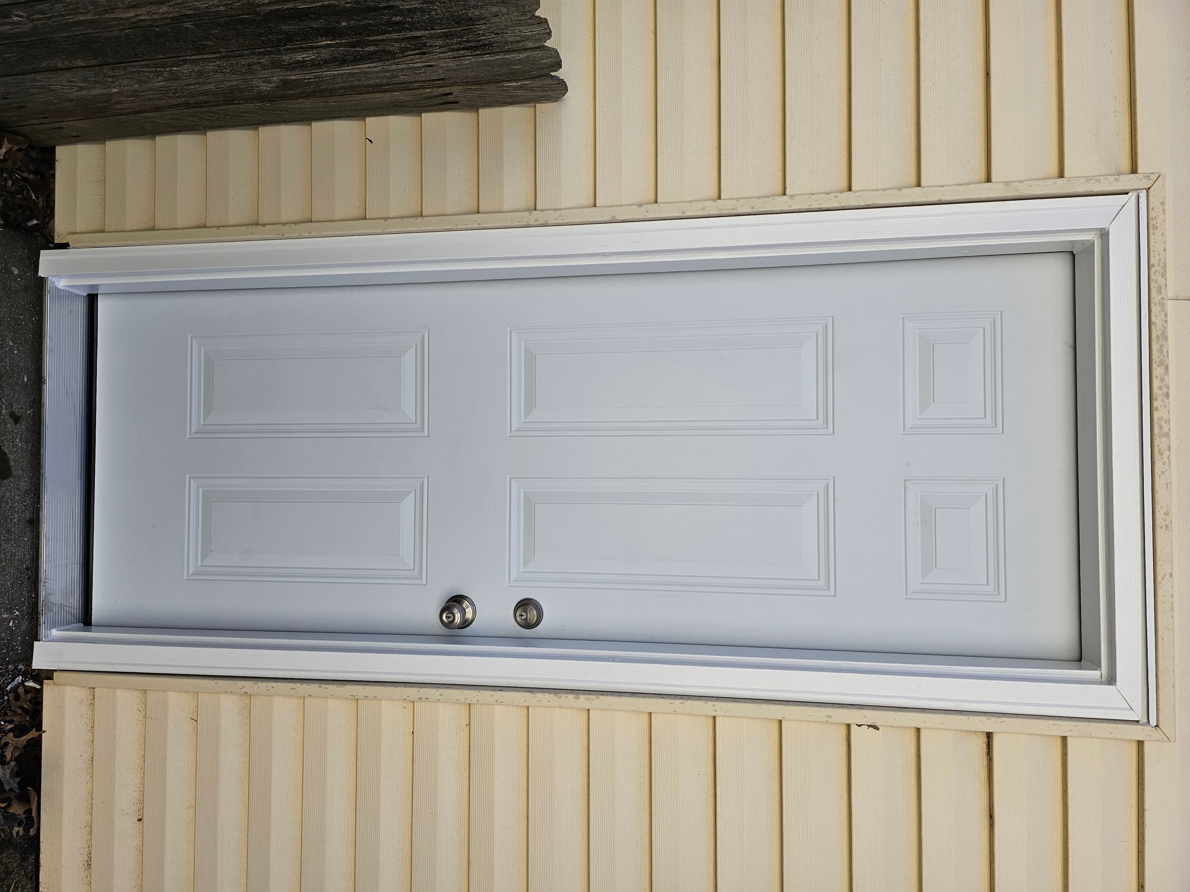 Exterior entry door and surrounding siding during a residential installation.