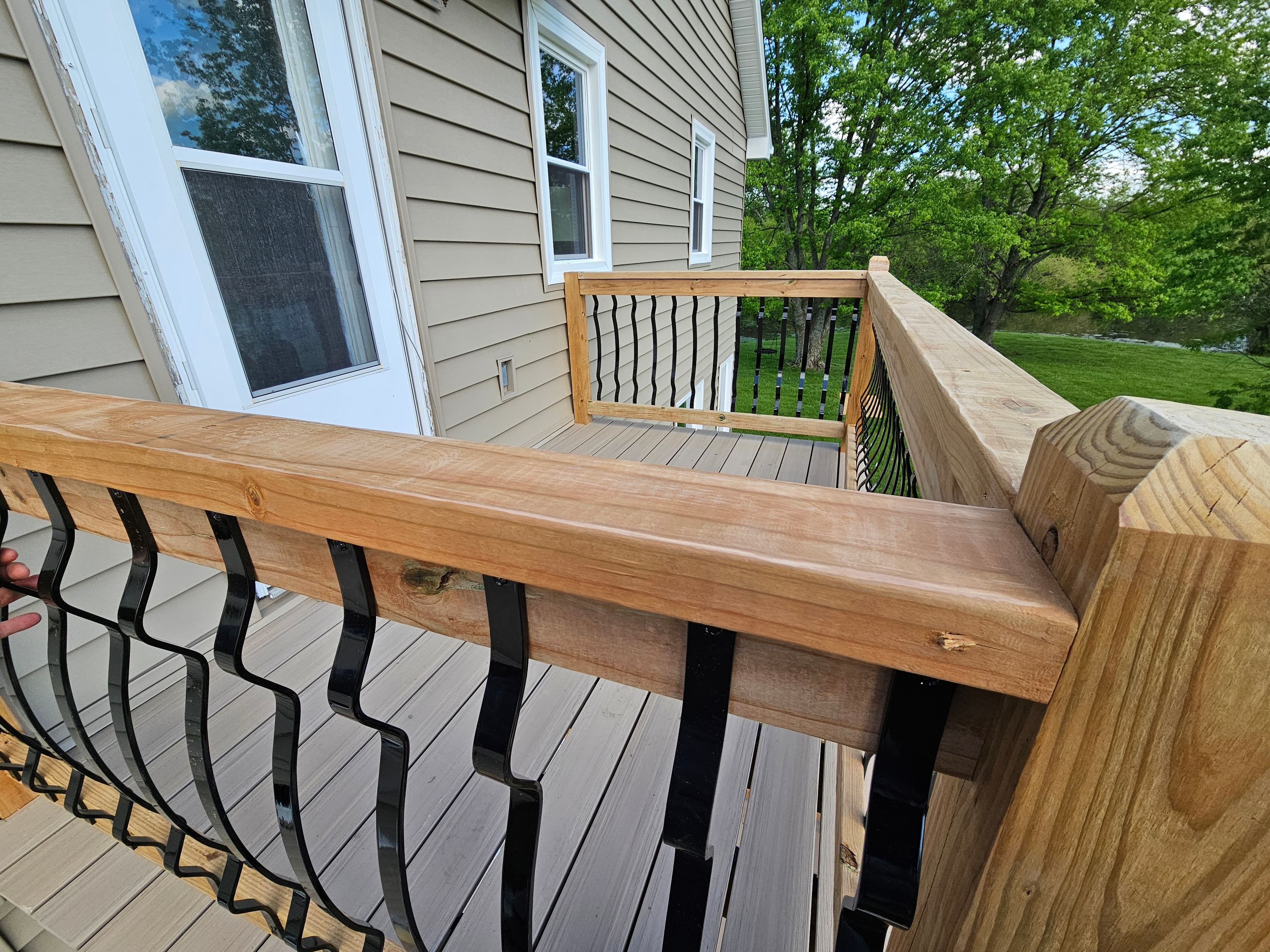 second level residential wood deck with stairs and black metal balusters.