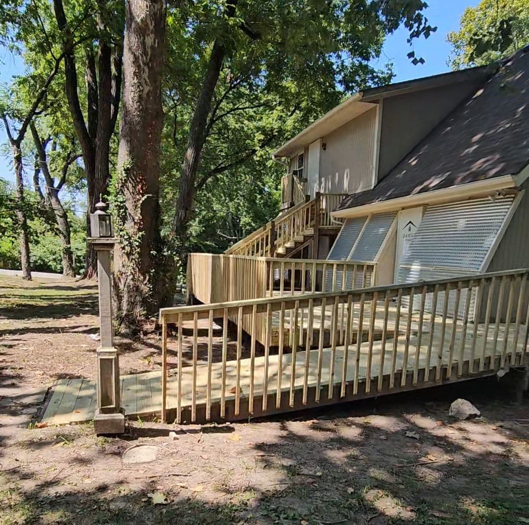 Residential wood deck and ramp structure wrapping around house exterior.