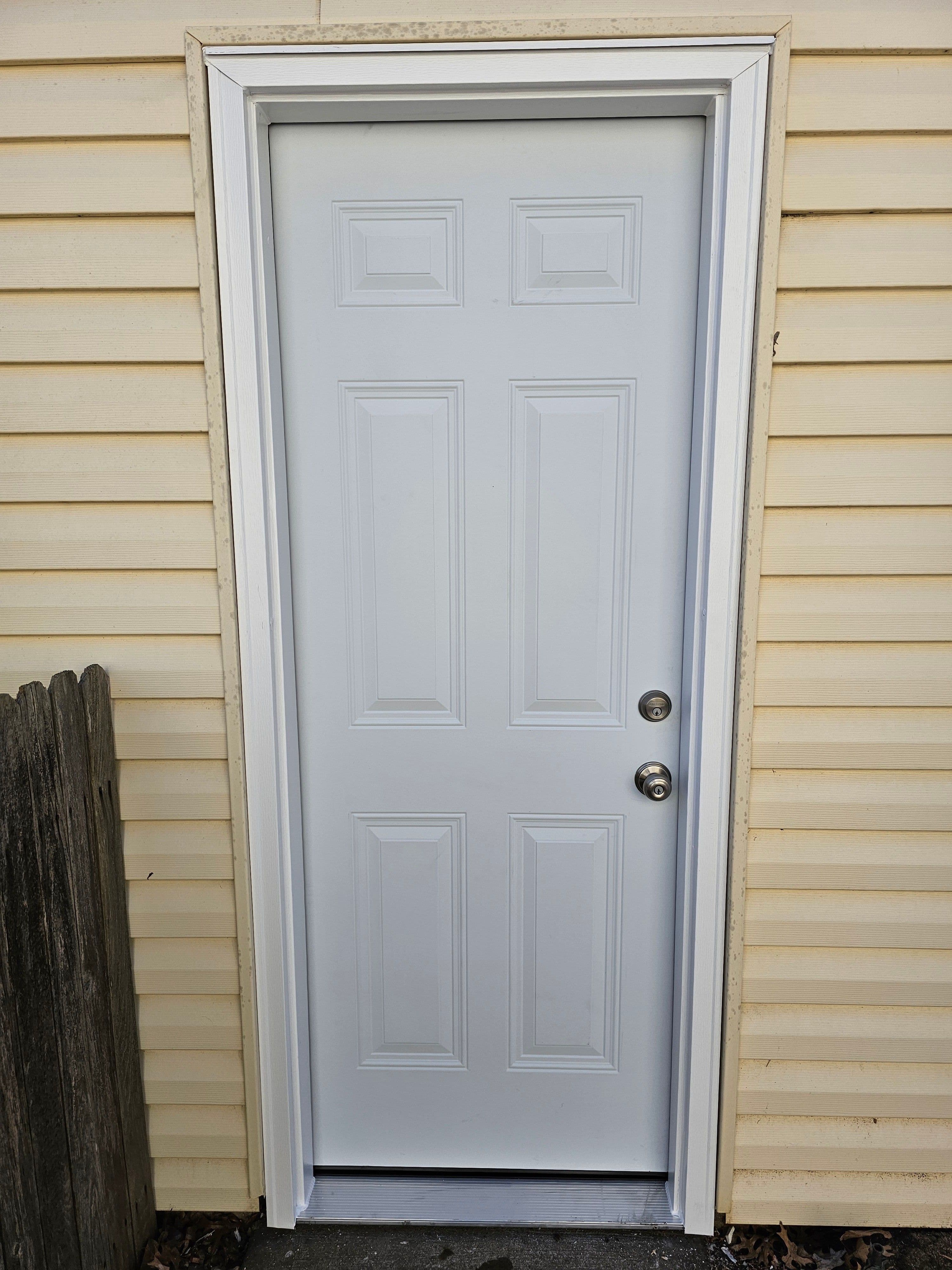 Exterior entry door and surrounding siding during a residential installation.