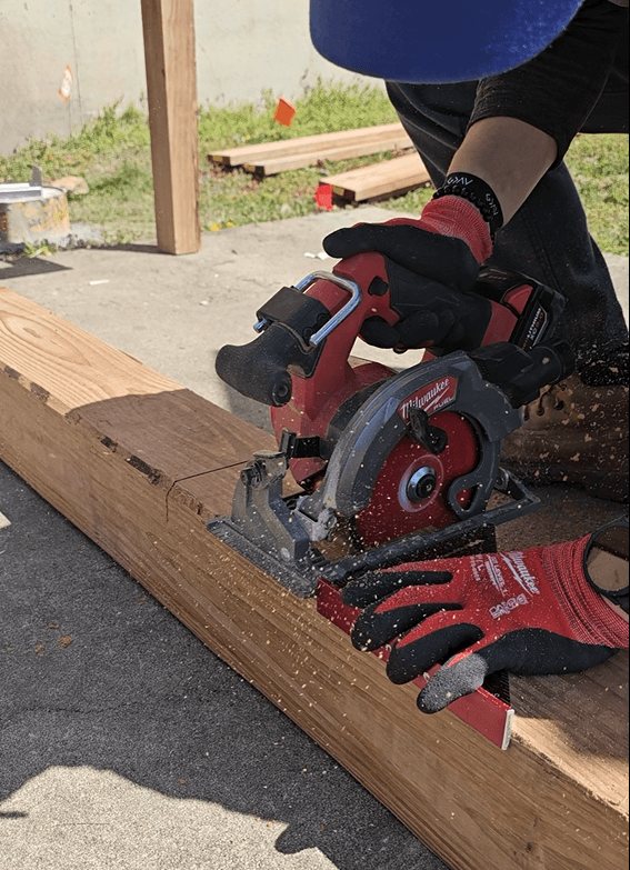 Worker using a circular saw to cut lumber during deck construction.